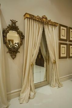 a room with white walls and gold framed pictures on the wall next to a mirror