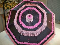 an umbrella decorated with pink and black fringes