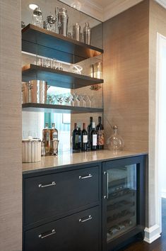 an empty bar with bottles and glasses on the top shelf, next to a wine glass cabinet