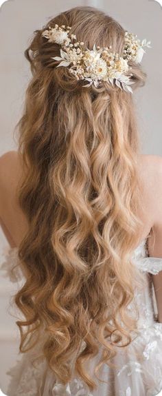 a woman with long curly hair wearing a flower headpiece in her hair, looking off to the side