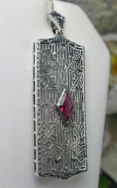 Rectangle Art Deco style pendant with fine lace filigree and a diamond shaped ruby red gemstone in the center of the filigree 1920s Jewelry, Mystic Fire Topaz, Natural Ruby Ring, Art Deco Movement, Art Deco 1920s, Pendant Diamond, Filigree Necklaces, Ruby Pendant, Star Ruby