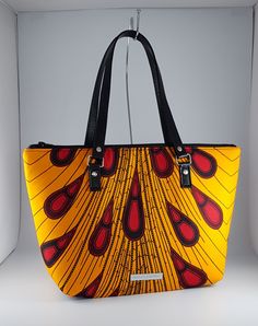 "\"Bag description:  This lovely bag is a perfect size for any occasion, with ample room for all your essentials when shopping, going to the office or on an evening out. The peacock design in yellow and wine also look great against a little black dress brightening the autumn day. This tote bag is a combination of Ankara African fabric and faux leather, fully lined waterproof canvas fabrics. The handles are long enough to fit comfortably on the shoulder or held by hand. Internally, this bag is fully lined with waterproof canvas and zippered pocket which fits your phone or other valuables. This bag is closed with a durable zip. Bag Style: Tote Fabric: African Wax Print Fabric - Ankara yellow and wine print fabric. 100% Cotton Lining: Waterproof canvas Hardware: Chrome  Handles: 24 inches in Yellow Satchel With Top Carry Handle For On-the-go, Yellow Satchel Bag For On-the-go, Multicolor Top Handle Bag With Zipper Closure, Yellow Large Capacity Bag For On-the-go, Yellow Top Handle Bucket Bag For Travel, Trendy Yellow Shoulder Bag, Trendy Yellow Satchel For Shopping, Yellow Rectangular Bag With Top Carry Handle, Trendy Yellow Double Handle Bag