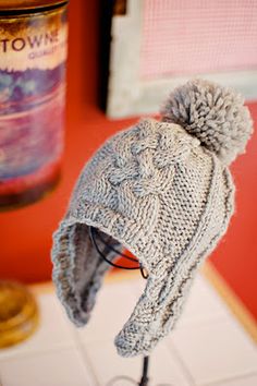 a knitted hat with a pom - pom sitting on top of a table