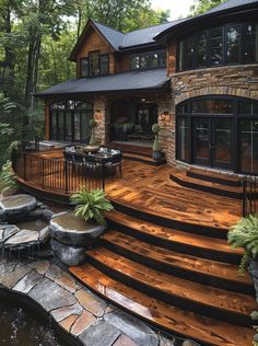 a wooden deck in front of a large house with stone steps leading up to it