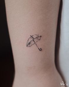 a small umbrella tattoo on the back of a woman's right leg, it is black and white