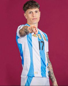 a man with tattoos pointing at the camera while wearing a soccer jersey and holding his hand out