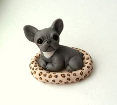 a figurine of a small dog sitting on a leopard print pillow with eyes wide open