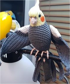 a crocheted bird sitting on top of a table next to a yellow helmet