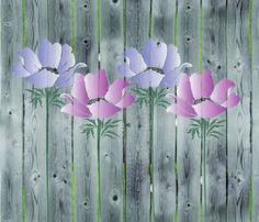 three pink and purple flowers sitting on top of a wooden fence