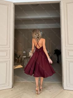 a woman in a red dress is walking through an open door with her back to the camera