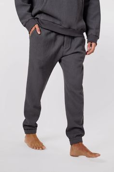 Elevate your loungewear game with the unisex Jet Set Jogger Pants from Afterlight Leisure. Made from 100% cotton waffle knit fabric, these stylish pants also feature terry cloth lining in the front and back pockets for added comfort. Each detail is thoughtfully-curated from the silver logo-embossed drawstring cord to the seashell button enclosed front placket and back pocket. Perfect for airplane loungewear or just relaxing at home, these joggers are a must-have for anyone who prioritises comfor Cotton Pants With Ribbed Cuffs For Lounging, Cotton Lounge Pants With Elastic Cuffs, Cotton Pants With Elastic Cuffs For Lounging, Cotton Bottoms With Ribbed Cuffs For Relaxation, Cotton Lounging Sweatpants, Cozy Cotton Sweatpants For Relaxation, Cotton Joggers With Ribbed Waistband For Relaxation, Cotton Lounge Pants With Tapered Leg, Relaxation Cotton Pants With Ribbed Waistband