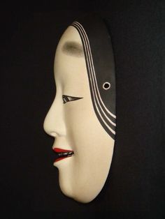 a white mask with black lines on it's face and eyes, in the dark