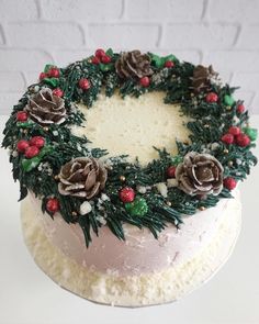 a christmas cake decorated with pine cones and holly wreaths is on the instagram page