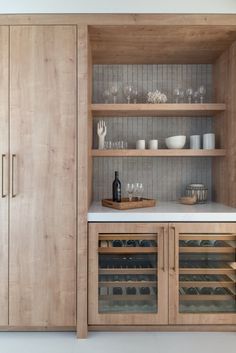 a wooden cabinet filled with lots of bottles and glasses on top of a white counter