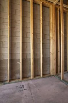 an unfinished room with wood framing in the wall and concrete flooring on the other side