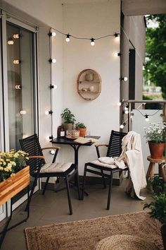 an outdoor patio with lights strung from the ceiling and potted plants on the table