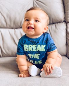 a baby is sitting on the couch and smiling