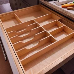 an open drawer in a kitchen filled with lots of drawers