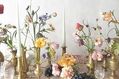 a table topped with lots of vases filled with different types of flowers and candles