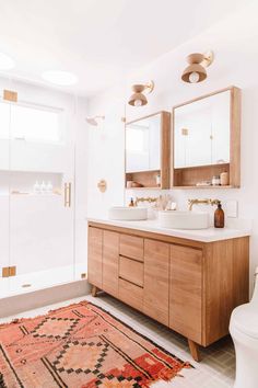 a bathroom with a rug, two sinks and mirrors on the wall in front of it