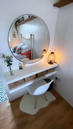 a mirror sitting on top of a white desk next to a lamp and bed in a room