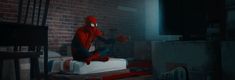 a spider man sitting on top of a bed in a room with brick walls and flooring