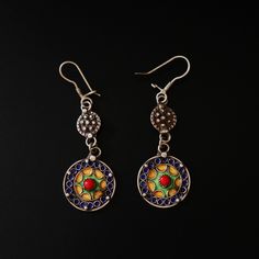 These exquisite handcrafted earrings showcase the rich cultural heritage of the Moroccan Amazigh people. Made from sterling silver, these dangle earrings feature a unique design with two circular elements connected by delicate links. The upper circle is adorned with intricate silver beadwork, while the larger lower circle displays vibrant enamel work in shades of blue, green, and yellow, surrounding a striking red stone accent. Dimensions & Weight: Length: Approximately 7.1 cm (2.8 inches) Width Traditional Artistic Design Drop Earrings, Handmade Fusion Round Earrings, Handmade Round Fusion Earrings, Traditional Dangle Jewelry With Artistic Design, Traditional Round Danglers With Matching Earrings, Artistic Metal Drop Earrings, Festive Multicolor Sterling Silver Earrings, Traditional Nickel-free Danglers, Traditional Sterling Silver Dangle Jewelry