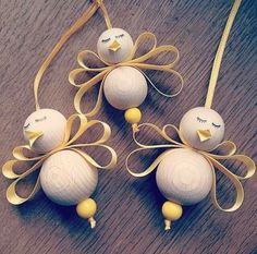 three white ornaments with yellow ribbons on a wooden table next to a string and ribbon