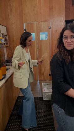 two women are standing in a kitchen and one is pointing at the other woman's hand