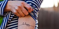 a woman with a tattoo on her arm that says, be happy in cursive writing