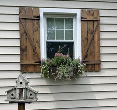 a bird house and window box on the side of a house with shutters open