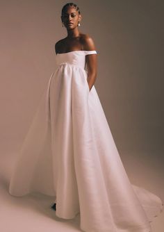 a woman in a white wedding dress posing for the camera with her hands on her hips