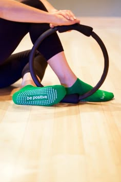 a woman sitting on the floor with a hoop around her ankles and wearing green socks