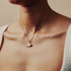 a woman wearing a necklace with a small bird on it