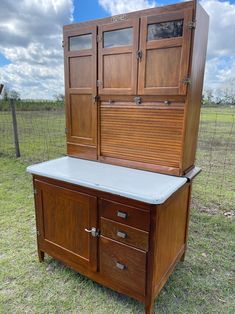 a large wooden cabinet sitting on top of a grass covered field