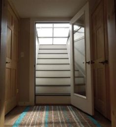 an empty hallway with stairs leading up to the second floor and light coming in through the window