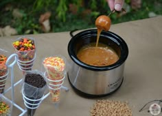 a person pouring candy into a crock pot with other candies in the background