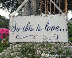 a sign that says, so this is love in front of some flowers and trees