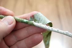 a hand holding a piece of fabric with a knot on it's end,