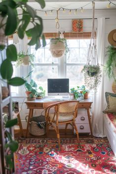 a desk with a laptop on it in front of a window filled with potted plants