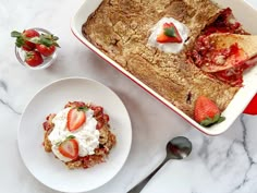 a white plate topped with fruit next to a casserole covered in whipped cream