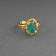 This big beautiful Columbian emerald is surrounded by diamonds set into 14k gold. This piece would make a gorgeous alternative engagement ring! Luxury Modern Yellow Gold Emerald Ring, Luxury Yellow Gold Oval Emerald Ring, Luxury Emerald Cluster Ring With Vvs Clarity, Exquisite Diamond Topaz Ring For Formal Occasions, Luxury Diamond Halo Topaz Ring, Luxury Emerald-cut Emerald Ring With Halo Design, Luxury Emerald Cut Emerald Ring With Halo Design, Luxury Cluster Ring With Emerald Cut And Halo Design, Luxury Emerald Rings With Halo Design