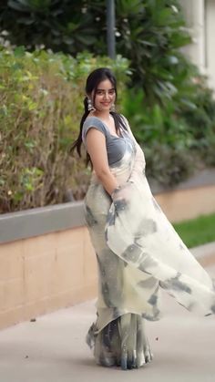 a woman is walking down the sidewalk wearing a dress and smiling at the camera with her hands on her hips