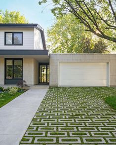 a white house with a large driveway and grass on the front lawn in front of it