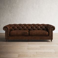 a brown leather couch sitting on top of a hard wood floor next to a white wall