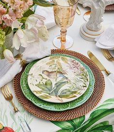 the table is set with plates, silverware and flowers