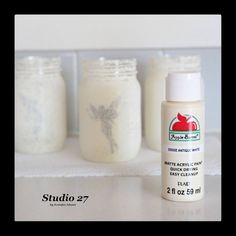 three jars with white acrylic paint sitting next to each other on a counter