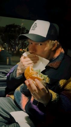 a man sitting in the back seat of a car eating a sandwich