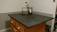 a kitchen counter with a candle and some flowers on top of it in front of a white wall