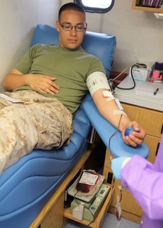 a man laying in a hospital bed with an oxygen tube attached to his arm and another person standing next to him